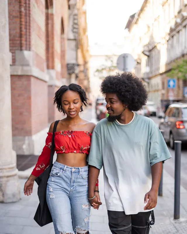 Couple afro souriant marchant main dans la main en ville