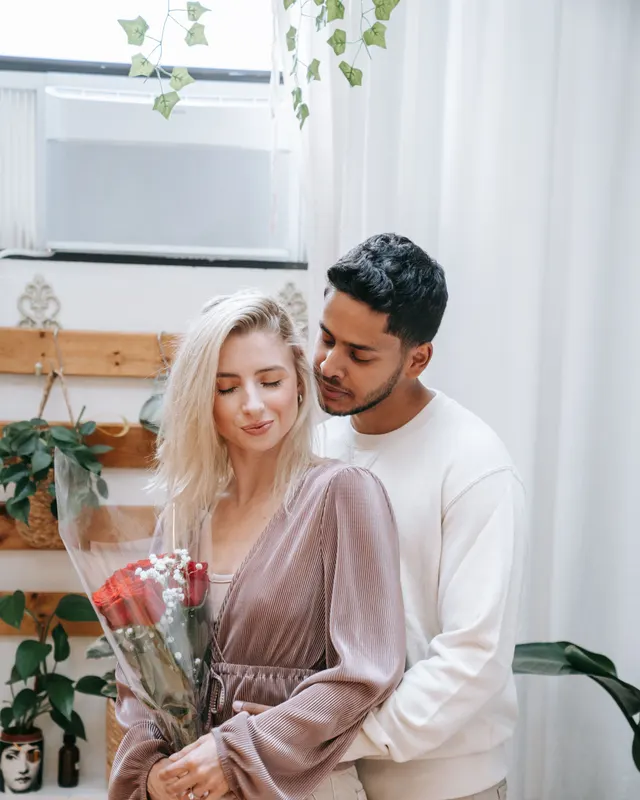 Couple mixte enlacé tenant un bouquet de roses rouges