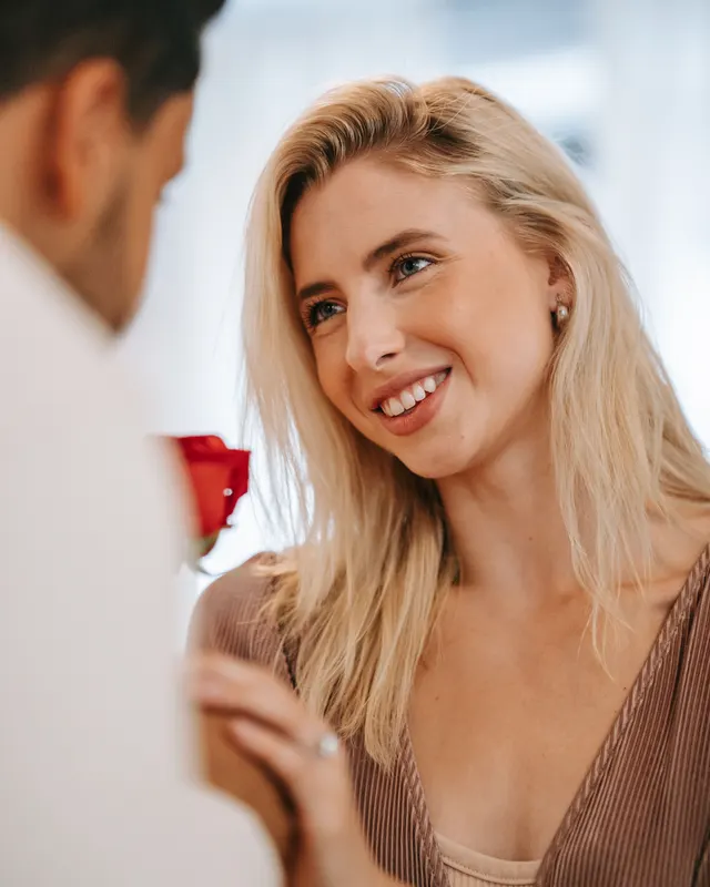 Femme souriante regardant son partenaire avec une rose