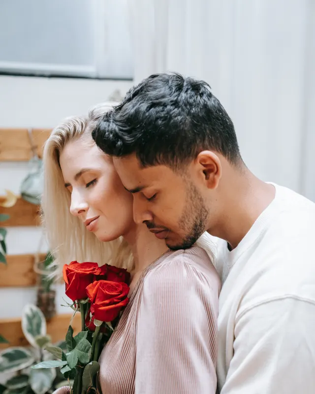 Couple mixte s'enlaçant tendrement avec des roses